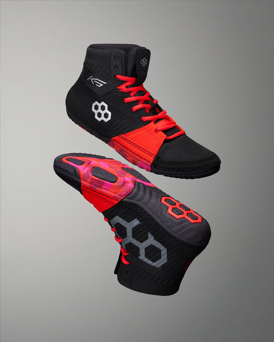 Black and red wrestling shoes with brand logos on a gray background