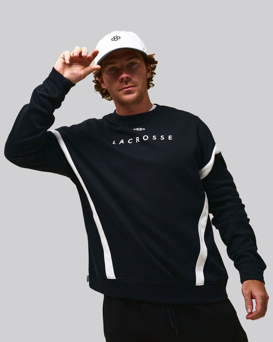 Pat Kavanagh wearing RUDIS lacrosse apparel, including a performance crewneck sweatshirt, athletic pants, and RUDIS hat.