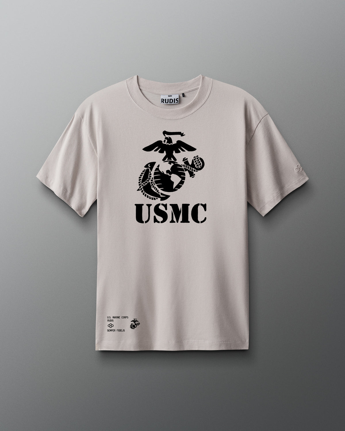 Front view of a light gray RUDIS T-shirt featuring a large black USMC eagle, globe, and anchor emblem with stenciled ‘USMC’ text below it. Additional small print near the hem includes 'U.S. Marine Corps,' 'RUDIS,' and 'Semper Fidelis.