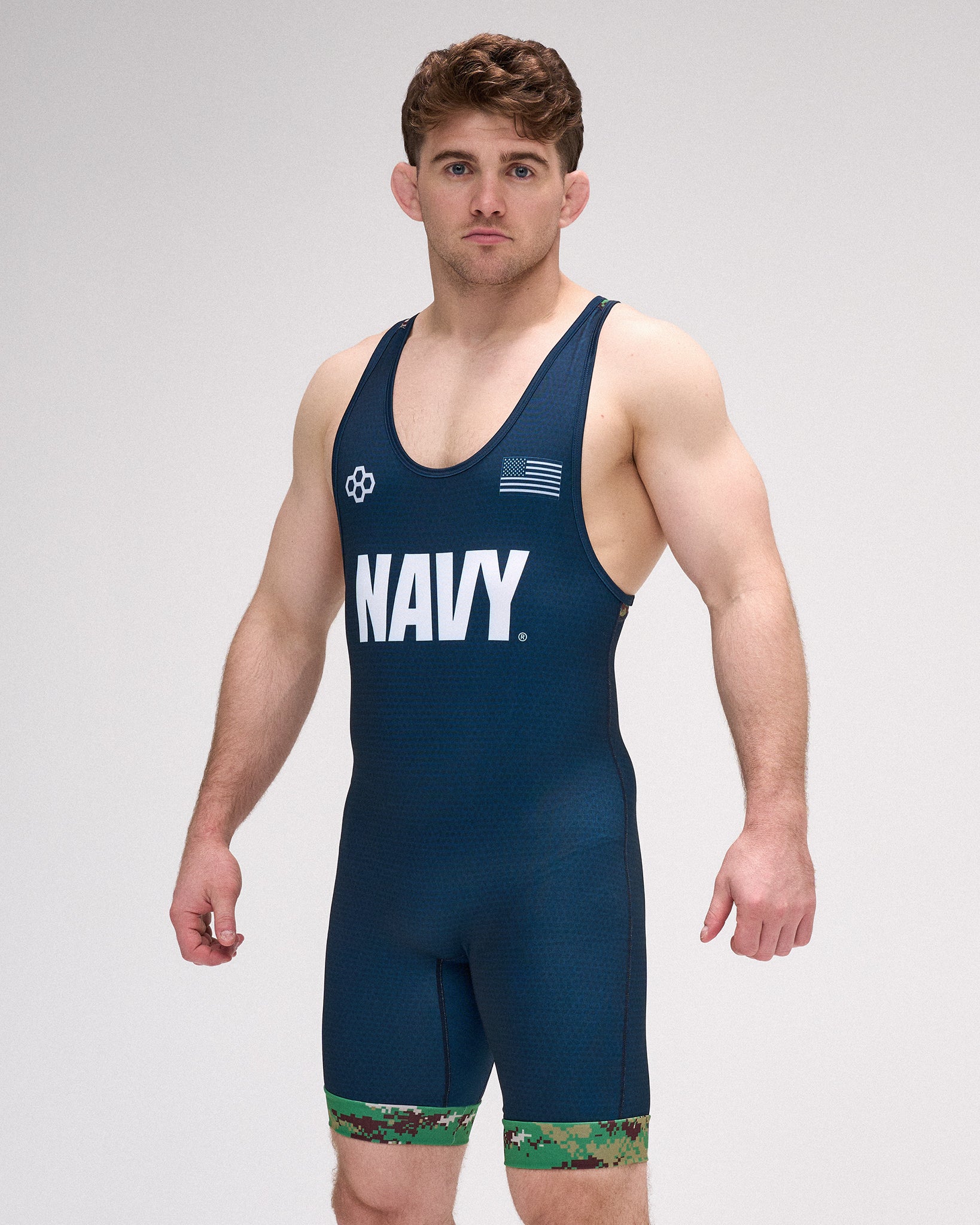 Man wearing a navy blue wrestling singlet with 'NAVY' printed on it against a gray background