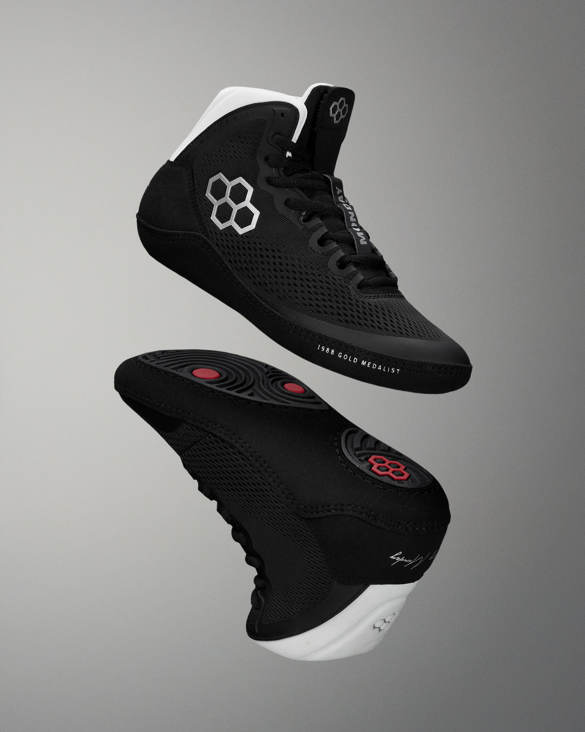 Black wrestling shoes with white soles on a gray background
