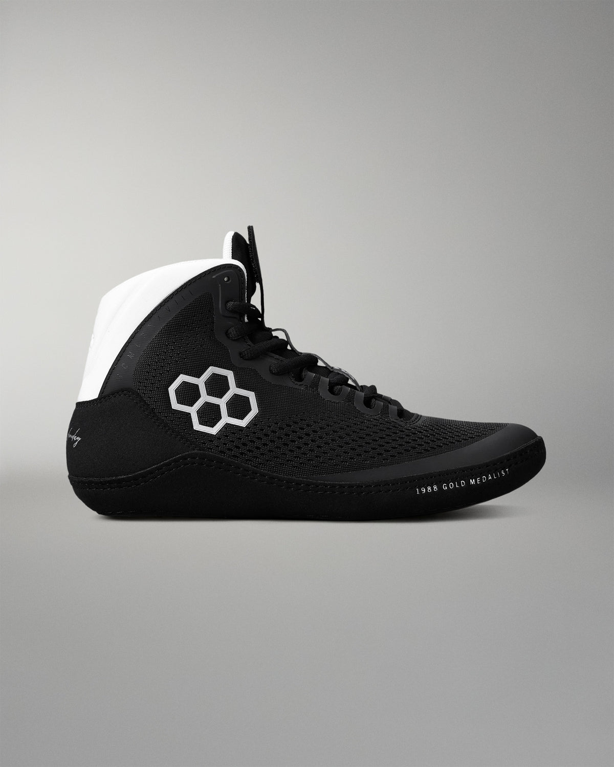 Black wrestling shoe with white accents on a gray background