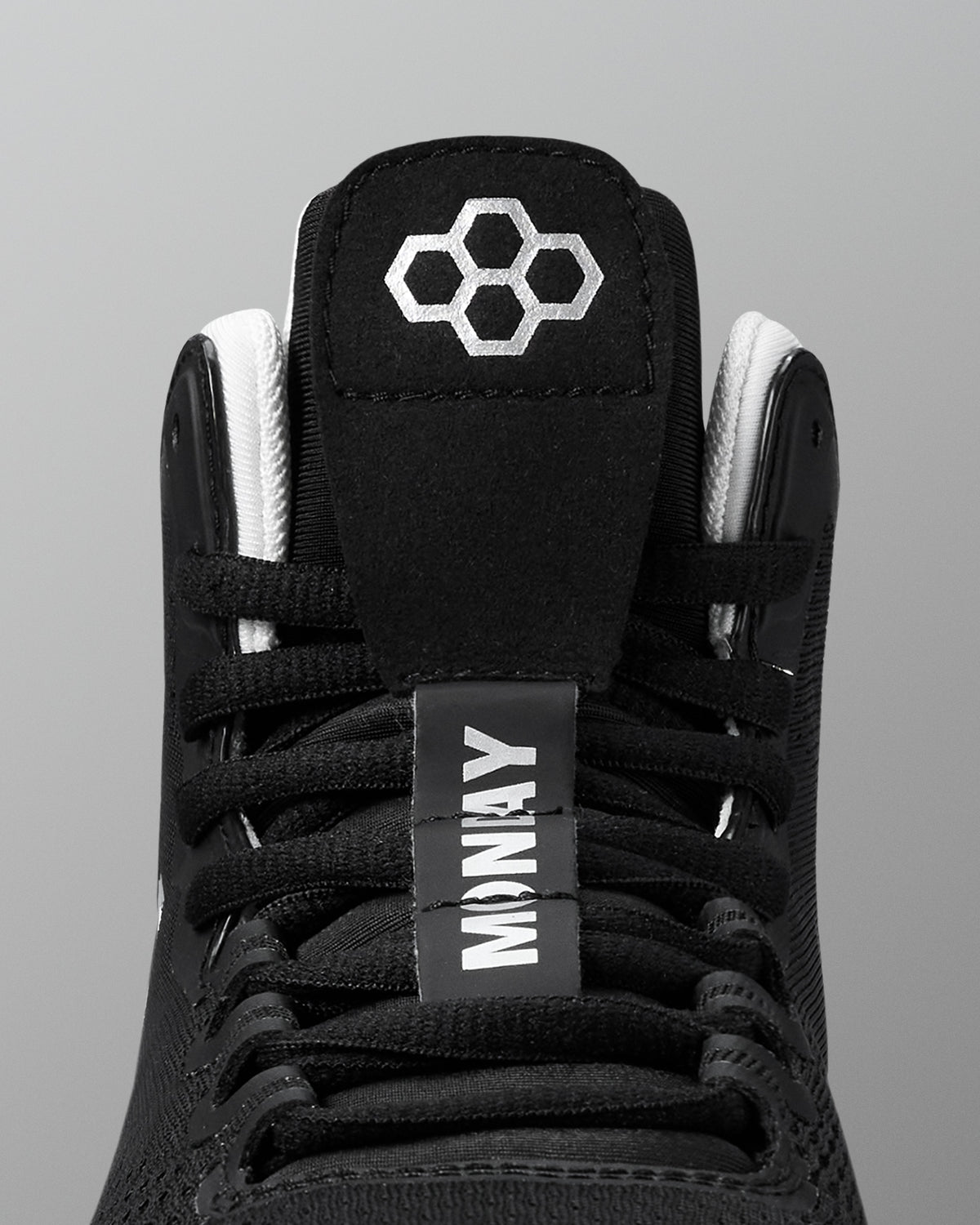 Black wrestling shoe with white laces and a visible brand logo on a gray background