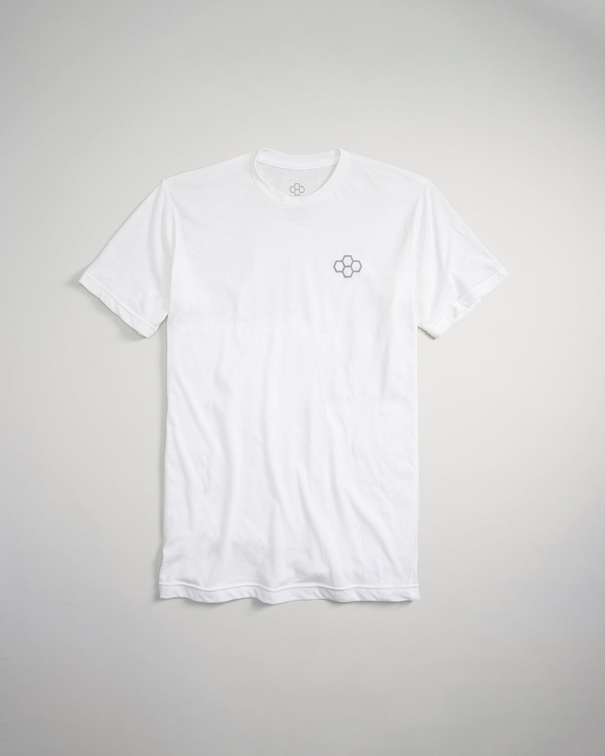 A plain white t-shirt featuring a subtle gray logo on the chest set against a light backdrop