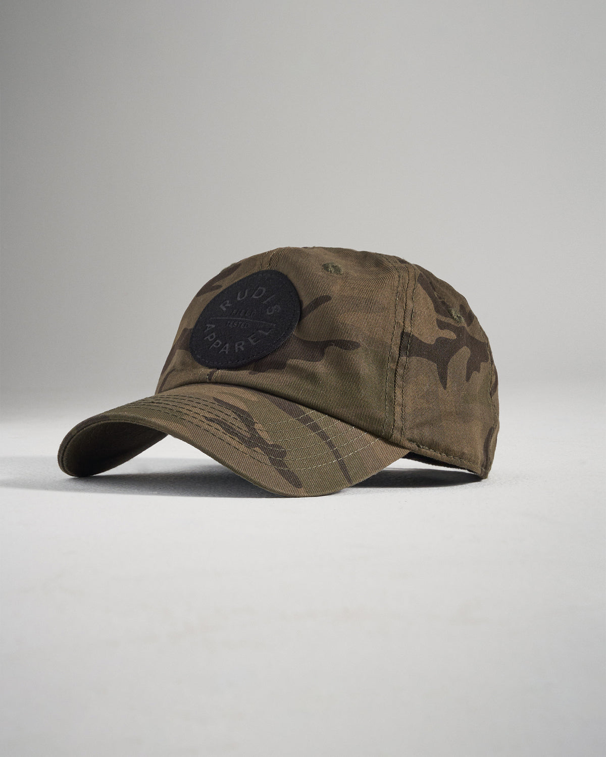 A stylish camo baseball cap featuring a round black patch with a brand name emblem designed for both casual wear and outdoor activities