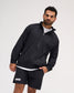 A man wearing a black full-zip jacket and matching black shorts with white Lacrosse branding, posed against a light gray studio background.