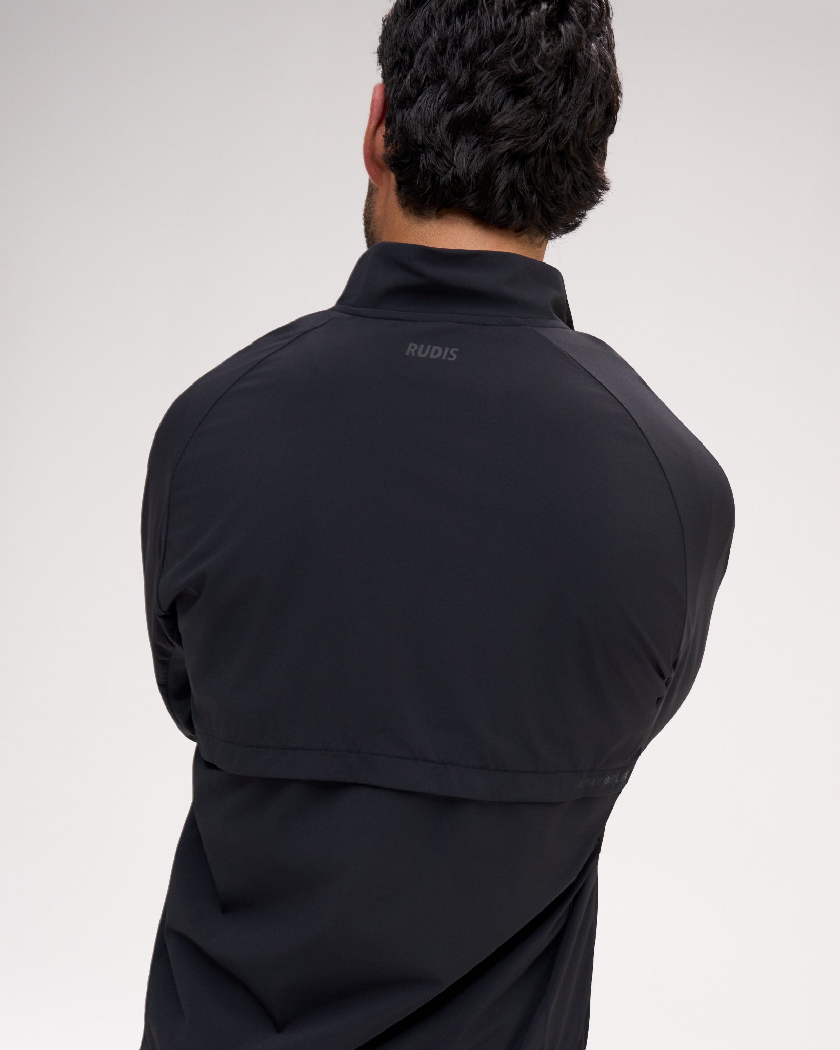 Rudis black athletic quarter-zip jacket shown from the back on a model, featuring a subtle gray brand logo on the upper neck.