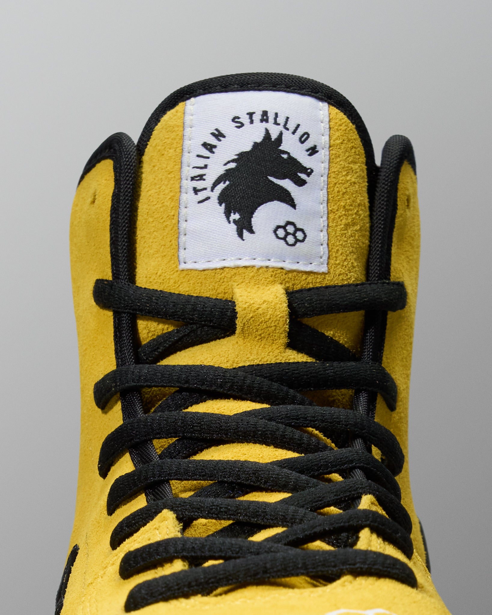 Close-up of the yellow RUDIS Rocky International Wrestling Shoe with black laces and Italian Stallion tongue label.