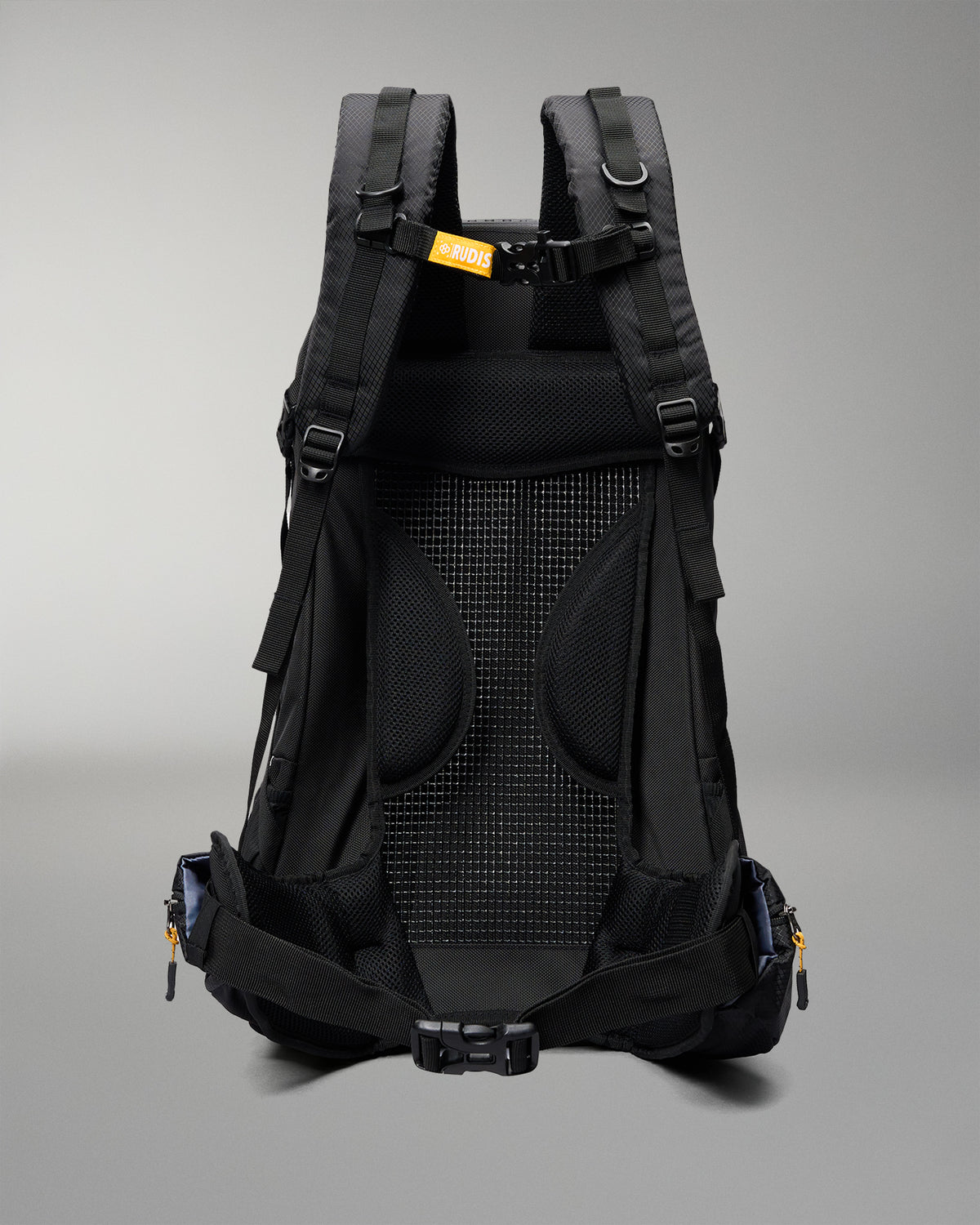 The back view of a black hiking backpack, showing the breathable mesh back panel, padded shoulder straps, and side compression buckles against a neutral gray background.