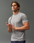 A young man wearing a fitted gray athletic t-shirt standing confidently with his hands together showcasing a modern minimalist style ideal for activewear or casual settings