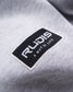 A close-up image of a gray garment featuring a rectangular logo patch that reads RUDIS A WAY OF LIFE in white text on a black background