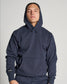 A young man wearing a navy hoodie with a front pocket and a casual confident expression posed against a plain light background