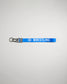A vibrant blue wrestling keychain featuring the word WRESTLING in bold white letters and a black clip for attachment