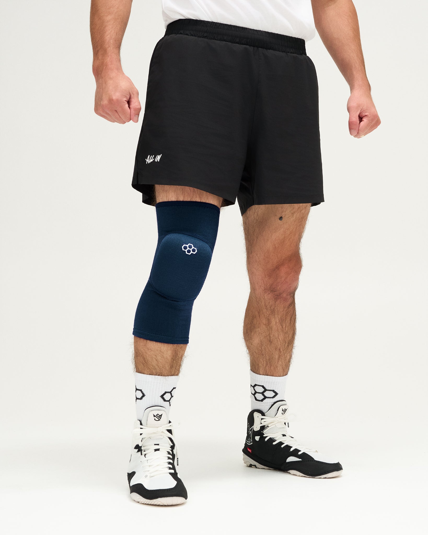 Person wearing blue knee pads and white sneakers on a plain background