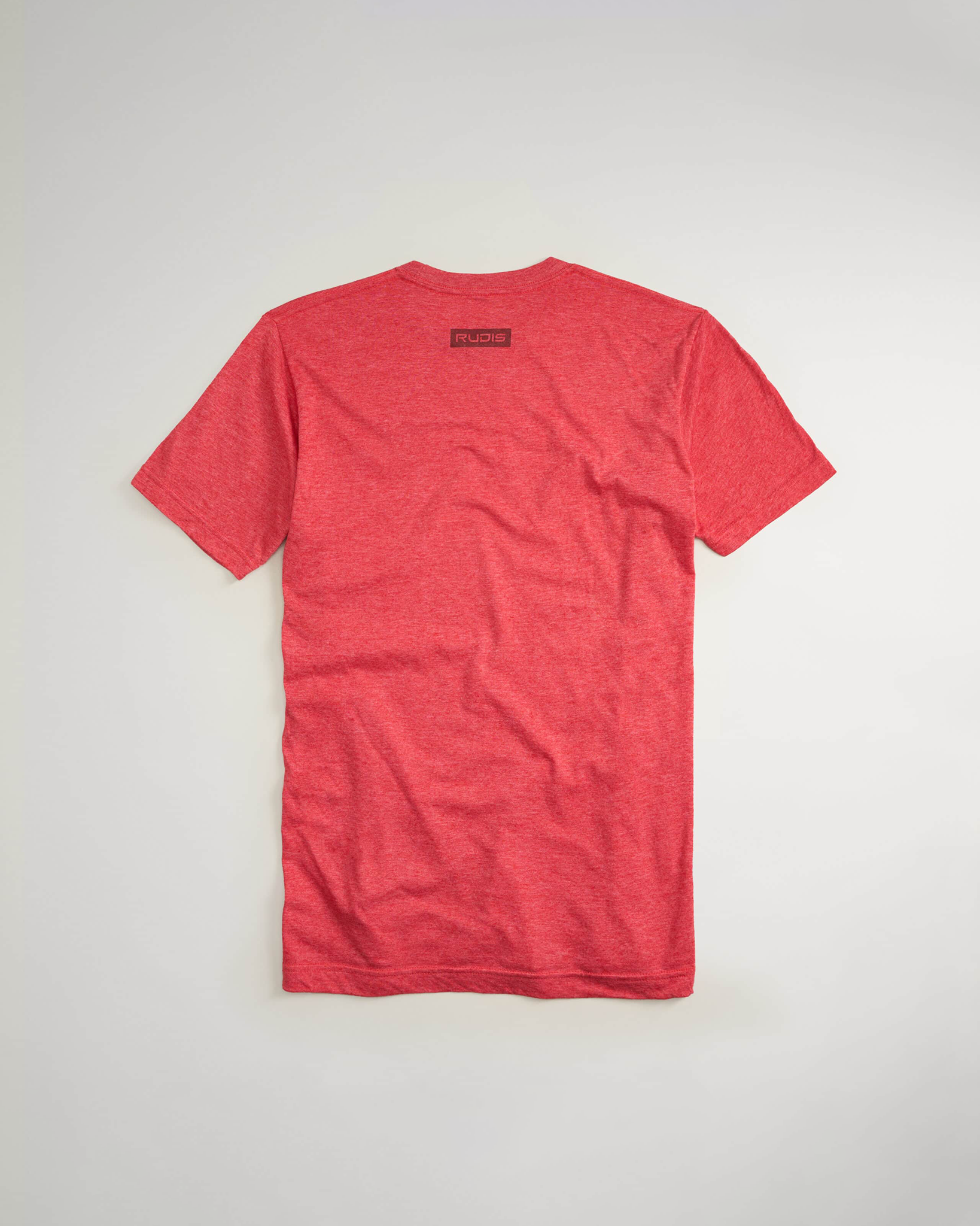 A back view of a vibrant red t-shirt featuring a simple design and the brand logo RUDIS near the neckline