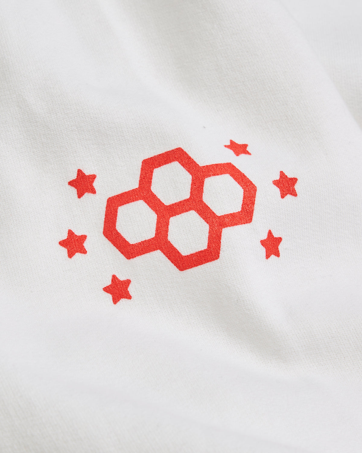 A minimalist design featuring a red graphic of interlocking hexagons and stars on a white fabric background