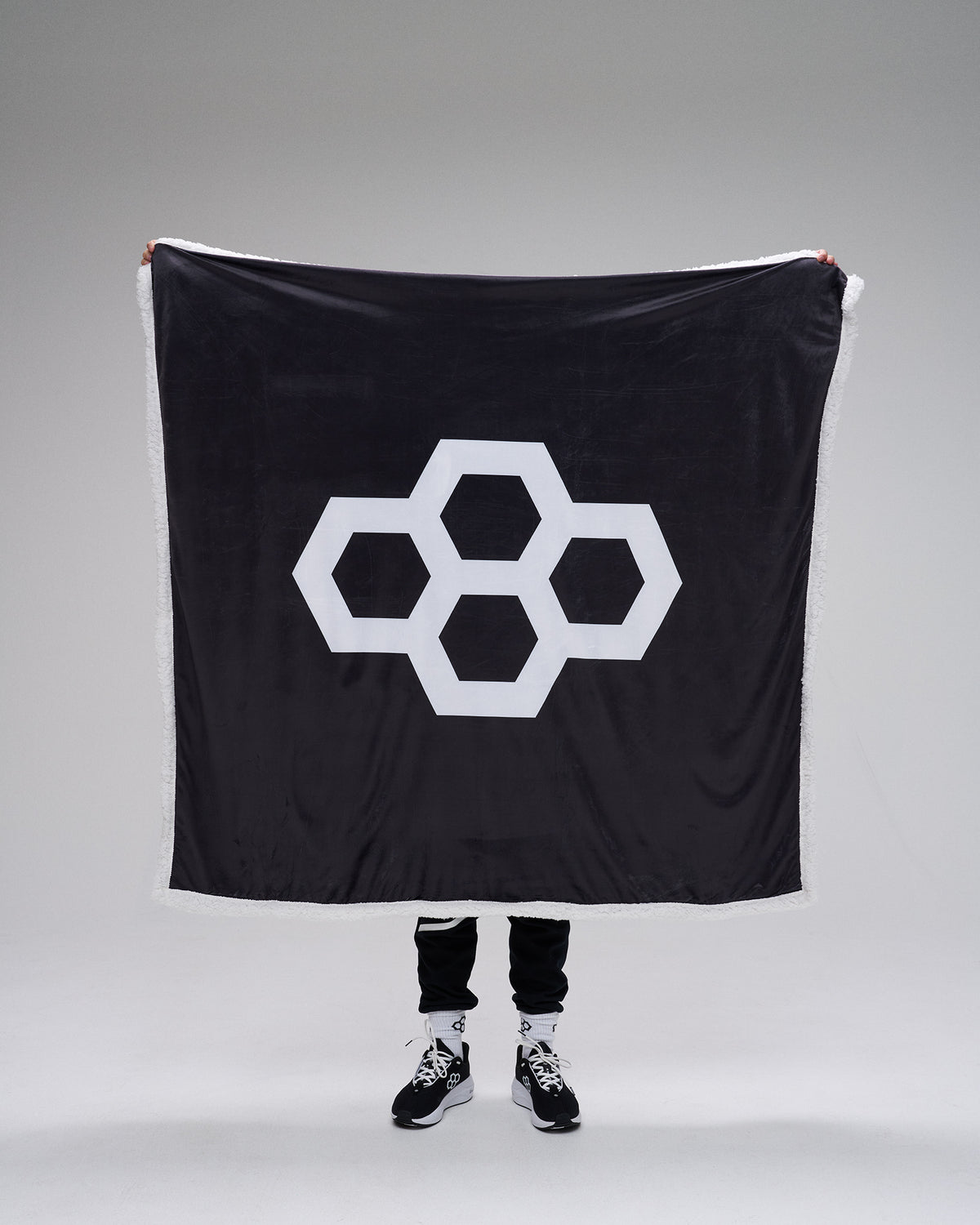 Person holding a black flag with a white geometric symbol on a gray background