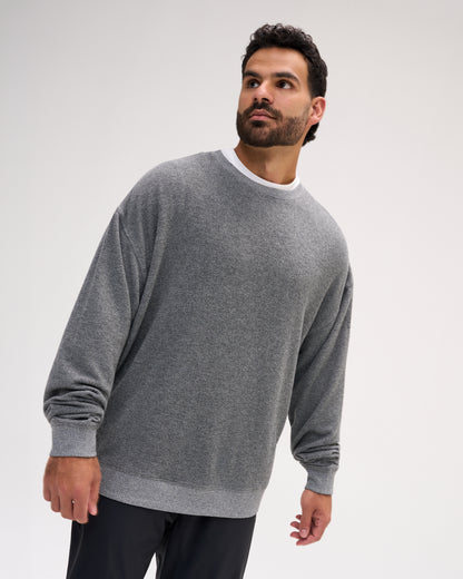 A man wearing a heather gray crewneck sweater with a contrasting white inner collar, photographed against a light gray studio background.
