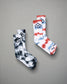 A pair of stylish socks featuring a tie-dye design in black and white alongside another pair in red white and blue with a modern logo