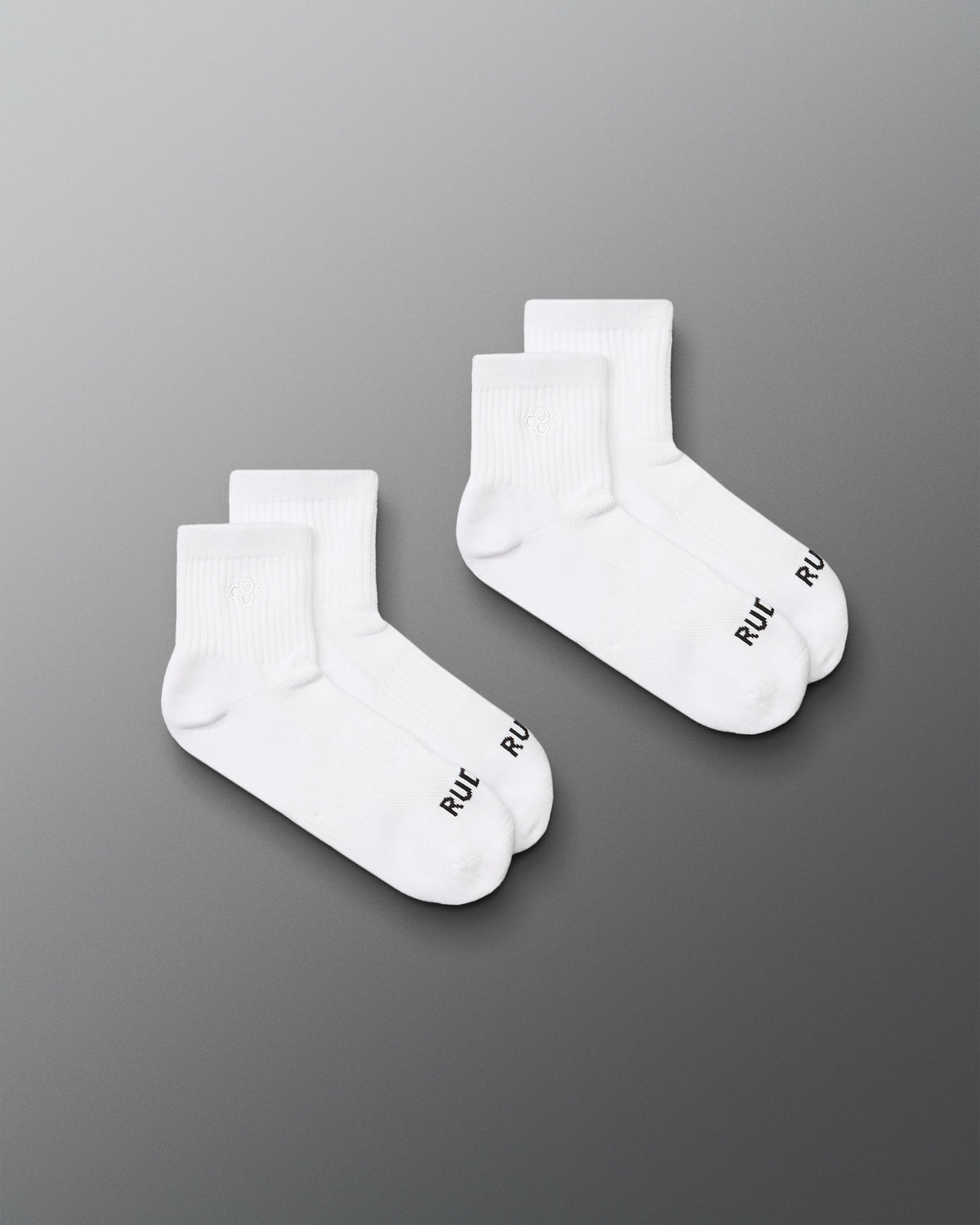 Two pairs of white socks with a brand logo on a gray background