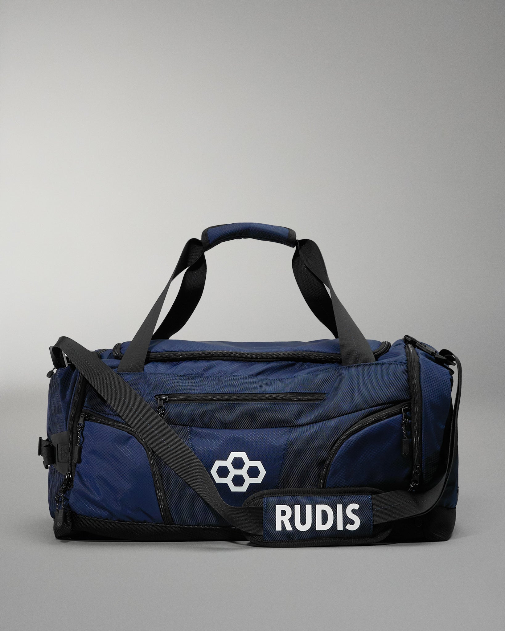 Blue wrestling duffel bag with black straps and 'RUDIS' branding on a gray background