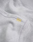 A close-up view of a light gray sweatshirt featuring unique yellow stitching accents on the side seam