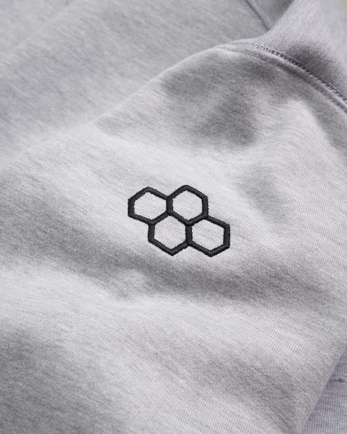 This image displays a close-up view of a grey fabric featuring an embroidered hexagonal logo in black conveying a modern and minimalist aesthetic