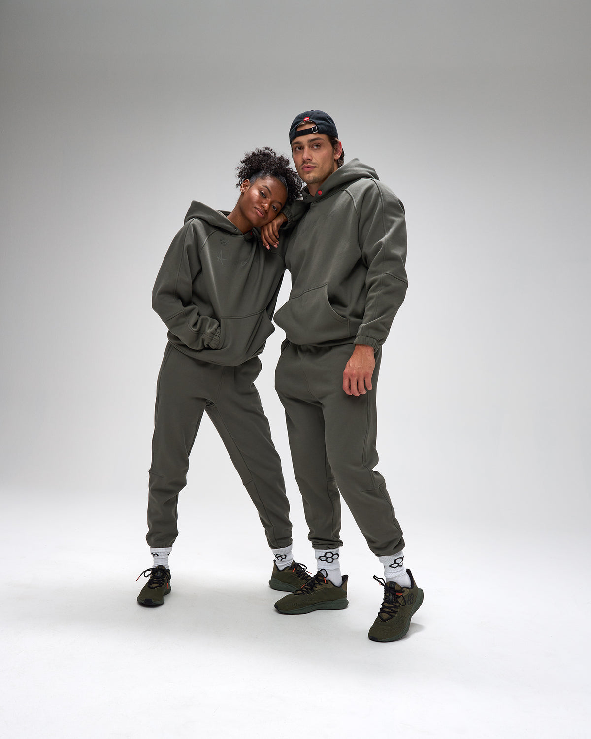 Two people wearing matching gray hoodies and pants on a white background