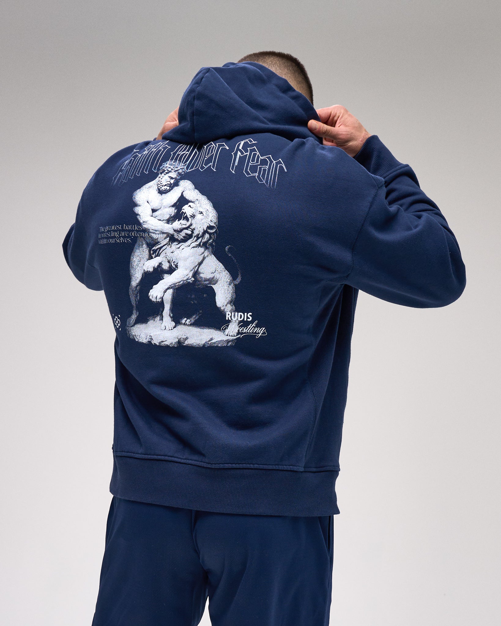 Person wearing a navy blue hoodie with a graphic design on the back against a gray background