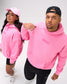 A man and a woman modeling matching bright pink hoodies with 'RUDIS' printed on the chest, against a clean white studio background.
