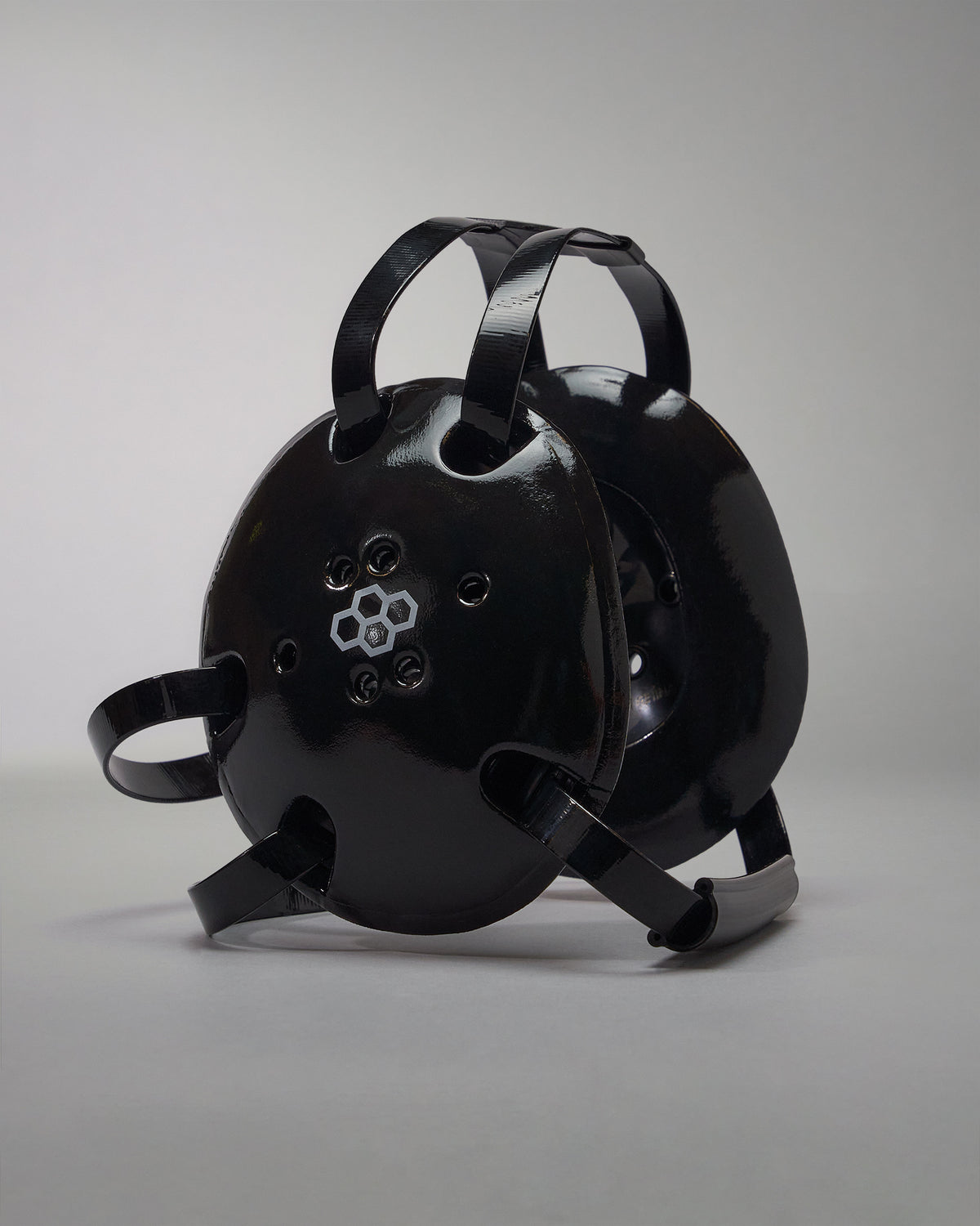 A rounded black wrestling headgear  with ventilation holes and adjustable straps for a secure fit, ideal for safety in industrial or recreational contexts.