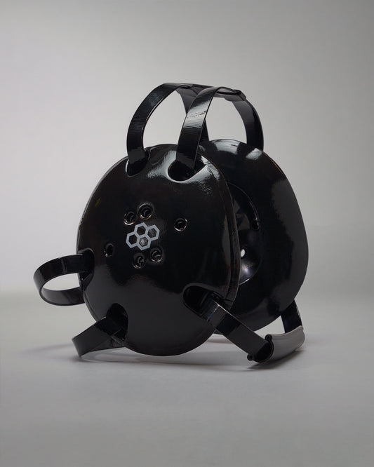 A rounded black wrestling headgear with ventilation holes and adjustable straps for a secure fit, ideal for safety in industrial or recreational contexts.