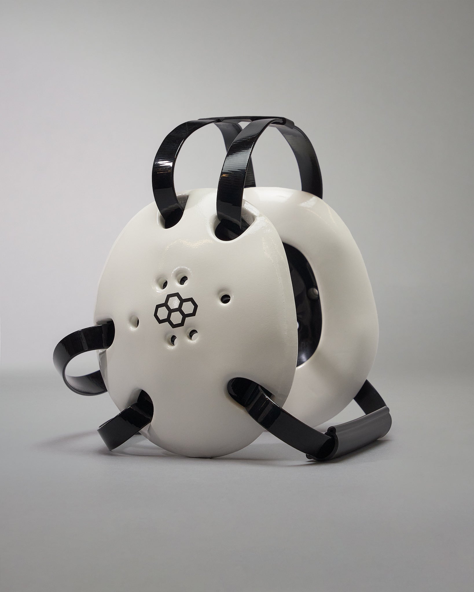 WHITE WRESTLING HEADGEAR - A futuristic helmet with a white shell, black accents, and ventilation holes, presented against a gray background.