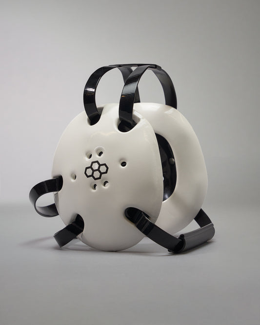 WHITE WRESTLING HEADGEAR - A futuristic helmet with a white shell, black accents, and ventilation holes, presented against a gray background.