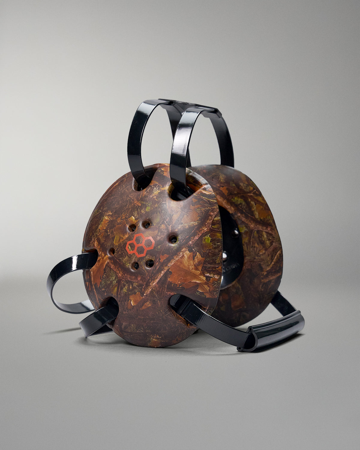 Rustic camo headgear with black handles on a gray background