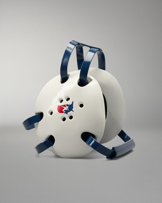 White protective wrestling headgear with blue straps on a gradient blue background. USA Wrestling logo on the headgear side