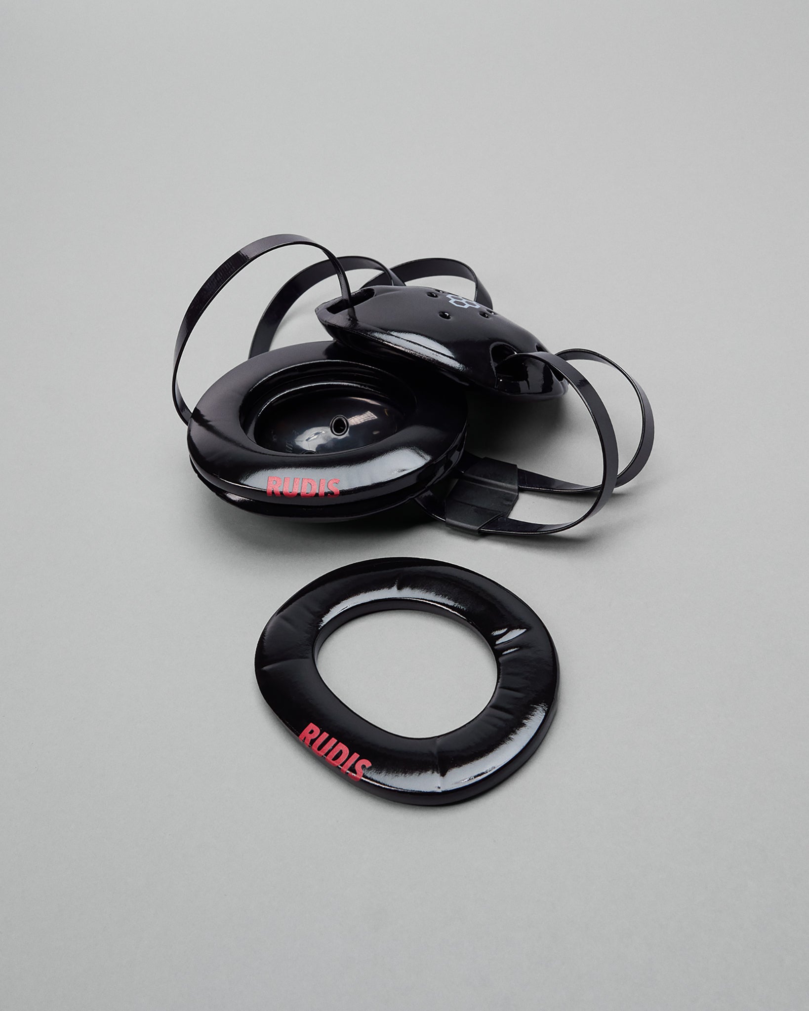Black RUDIS wrestling headgear extension pads on a gray background