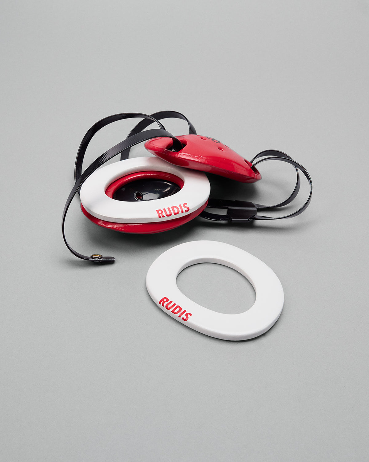 Red and white wrestling headgear extension pads with 'RUDIS' branding on a gray background