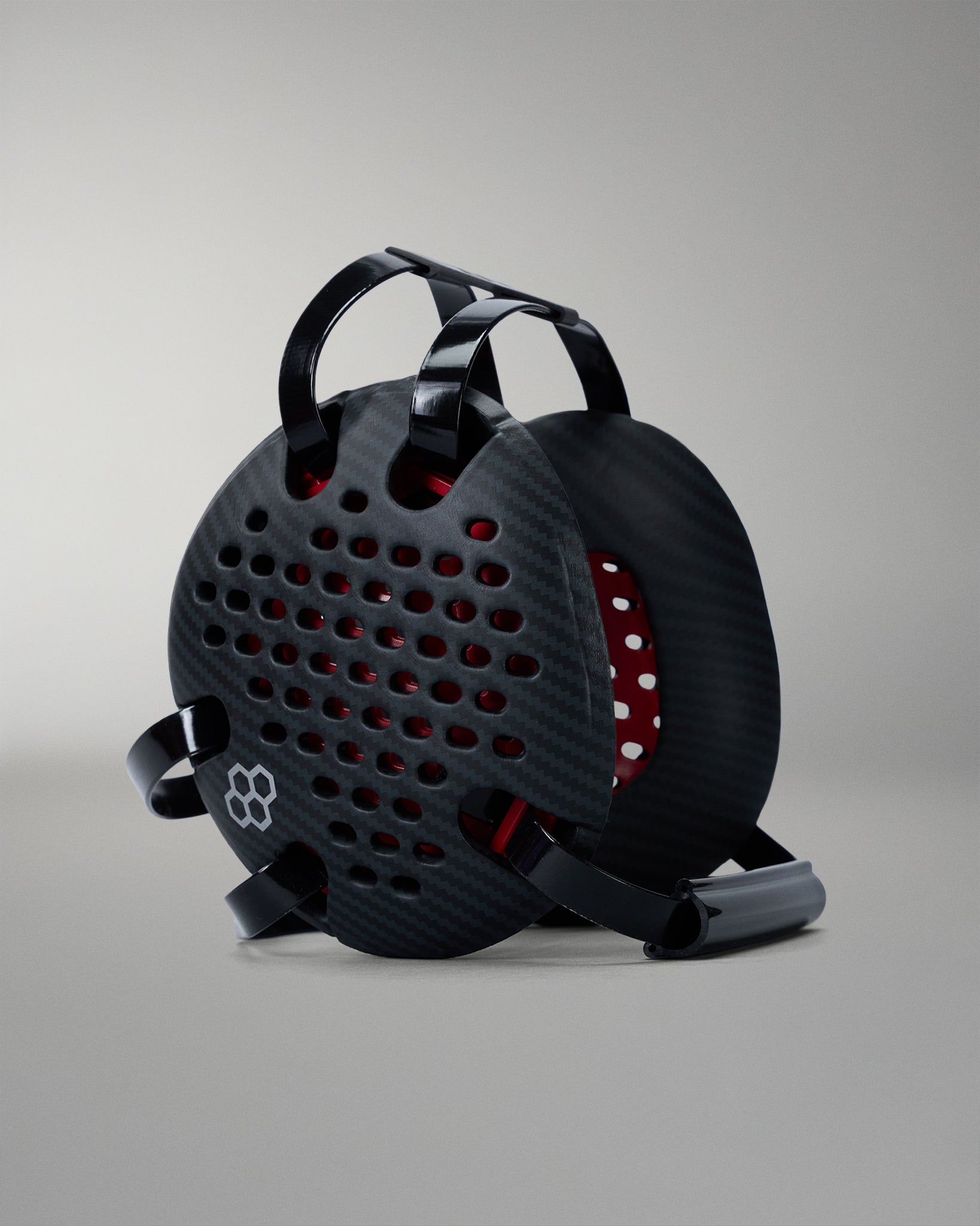 Black wrestling headgear with red interior on a gray background