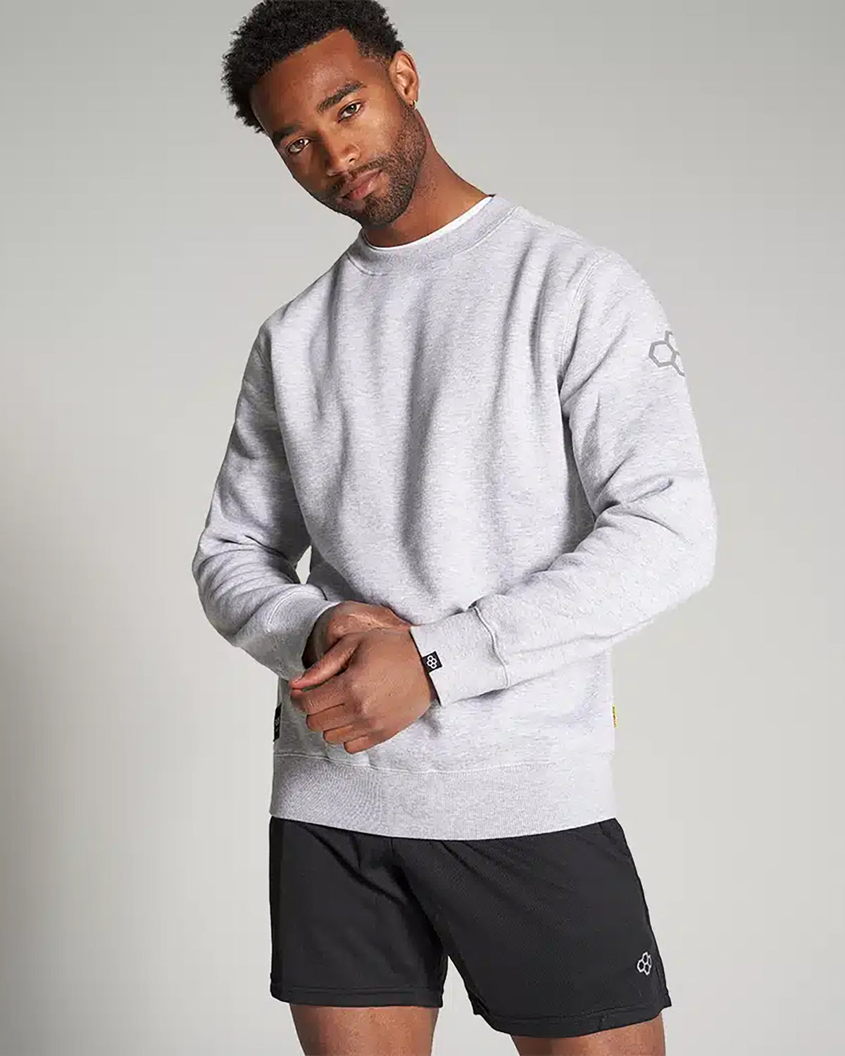 A man models a casual gray sweatshirt paired with black shorts showcasing a relaxed yet stylish look
