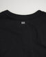 A close-up view of the back of a black t-shirt featuring a minimalist white logo design positioned below the neckline