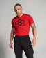 A fit man wearing a red t-shirt with a black graphic design and black athletic pants poses confidently against a light gray background