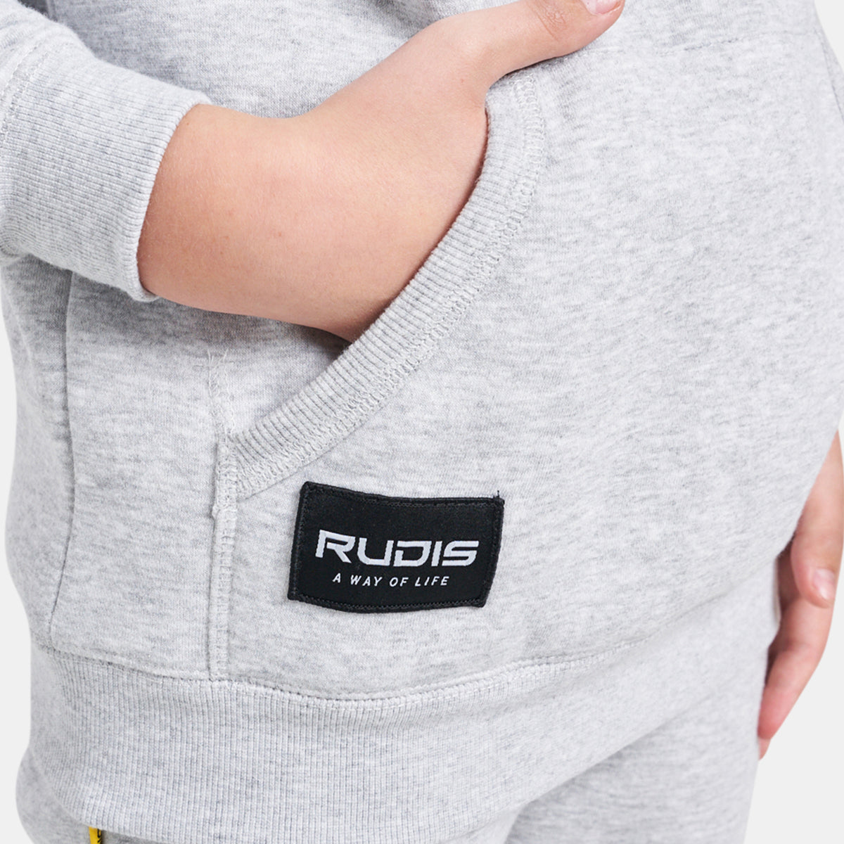 A close-up view of a childs gray sweatshirt featuring a pocket and a RUDIS label
