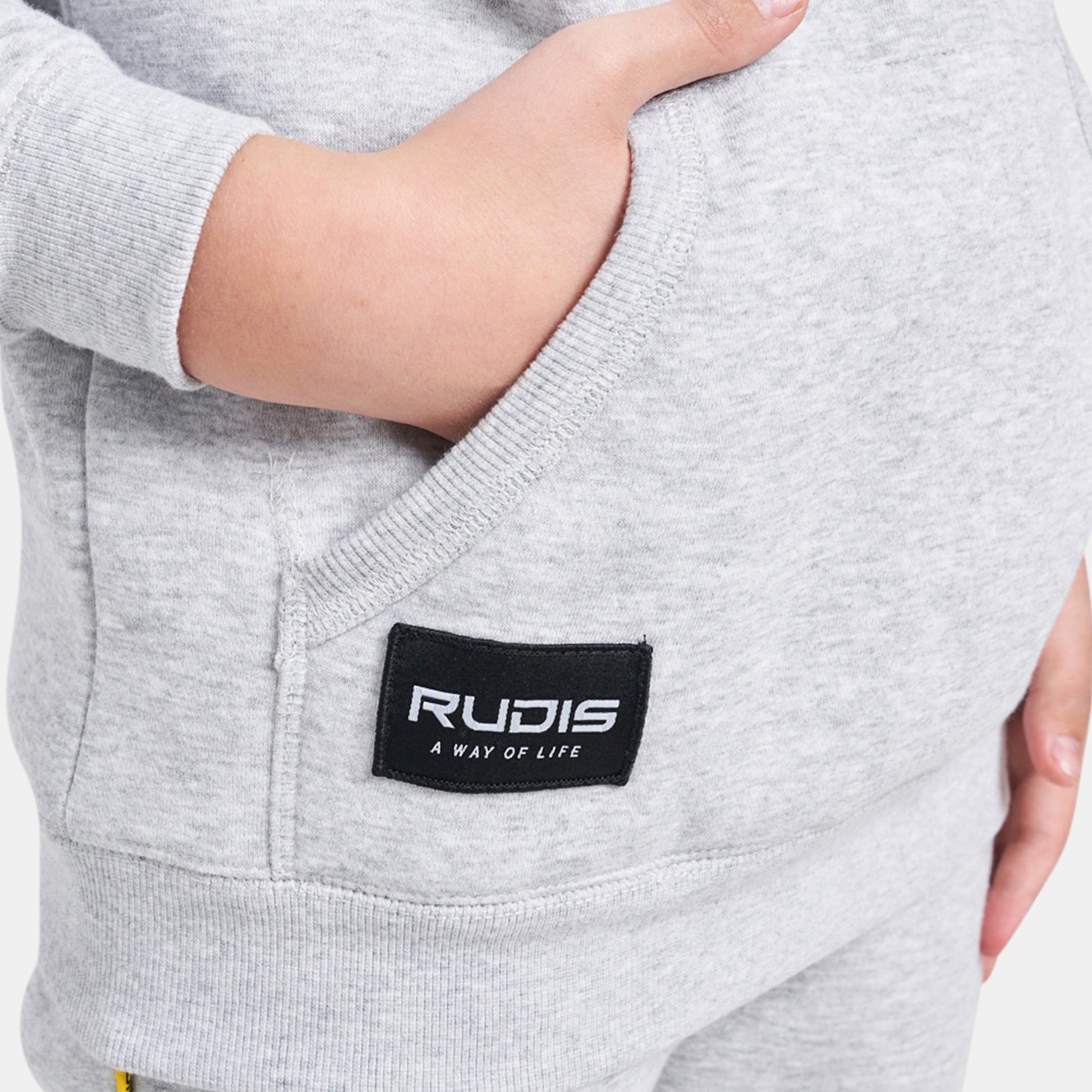 A close-up view of a childs gray sweatshirt featuring a pocket and a RUDIS label