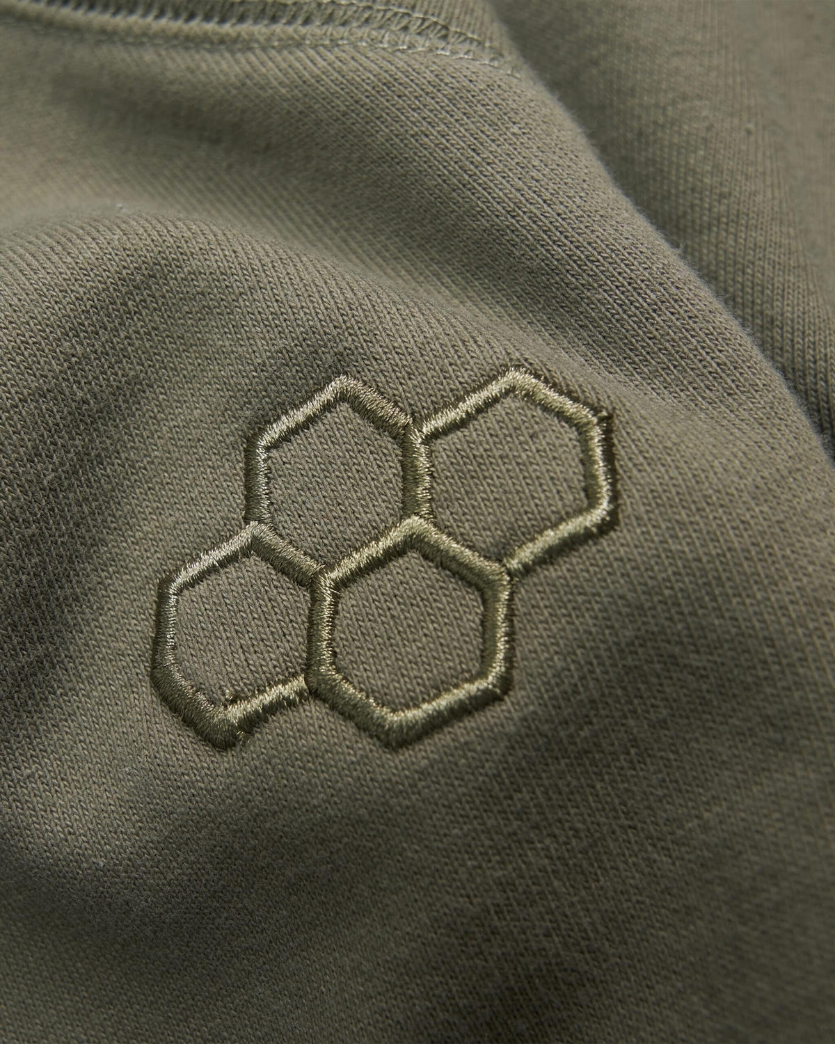 Embroidered hexagonal pattern on olive green fabric highlighting a stylish and modern design element