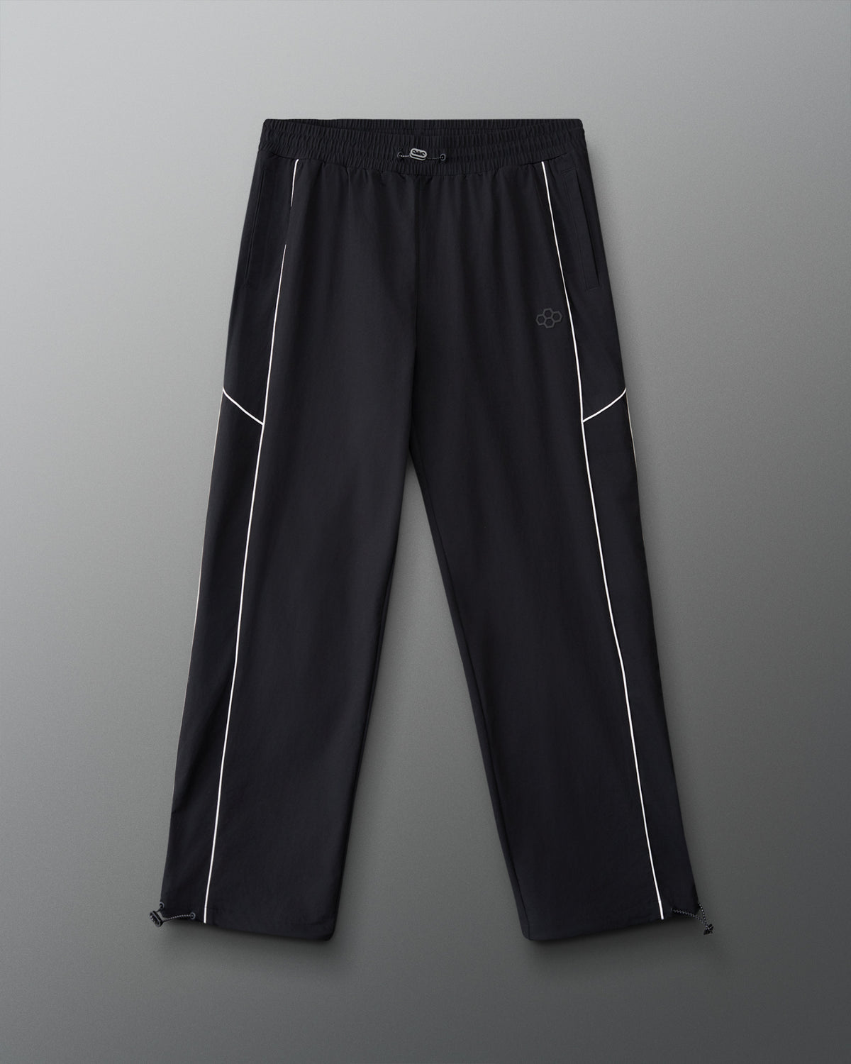 Front view of RUDIS Movement Podium Pants in black with white piping, elastic waistband, side pockets, and subtle RUDIS logo.