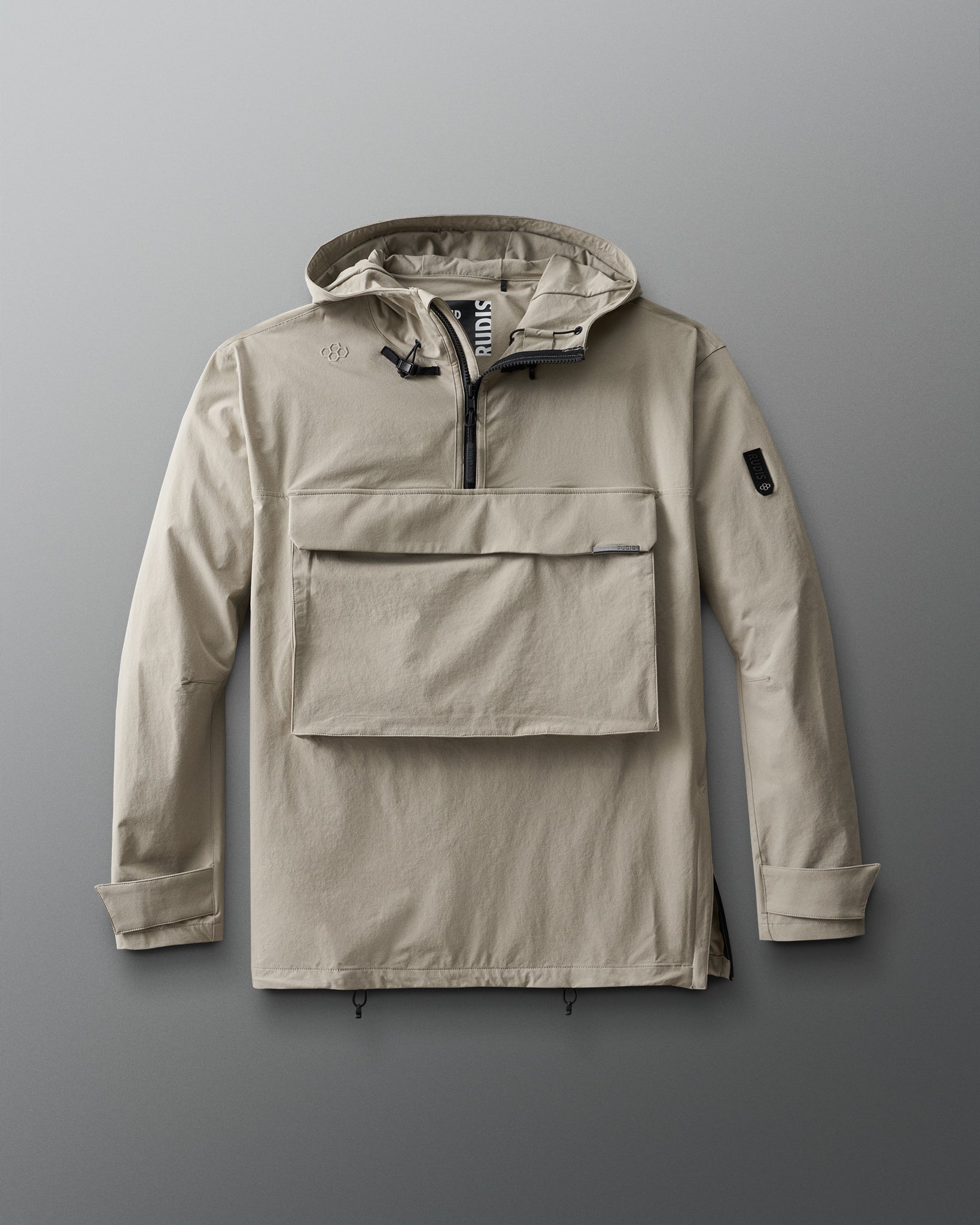 A beige, 1/4 zip jacket with a hood, designed for adults. The jacket features a front gear pocket, adjustable cuffs, hood, and waist, and is displayed on a grey background.