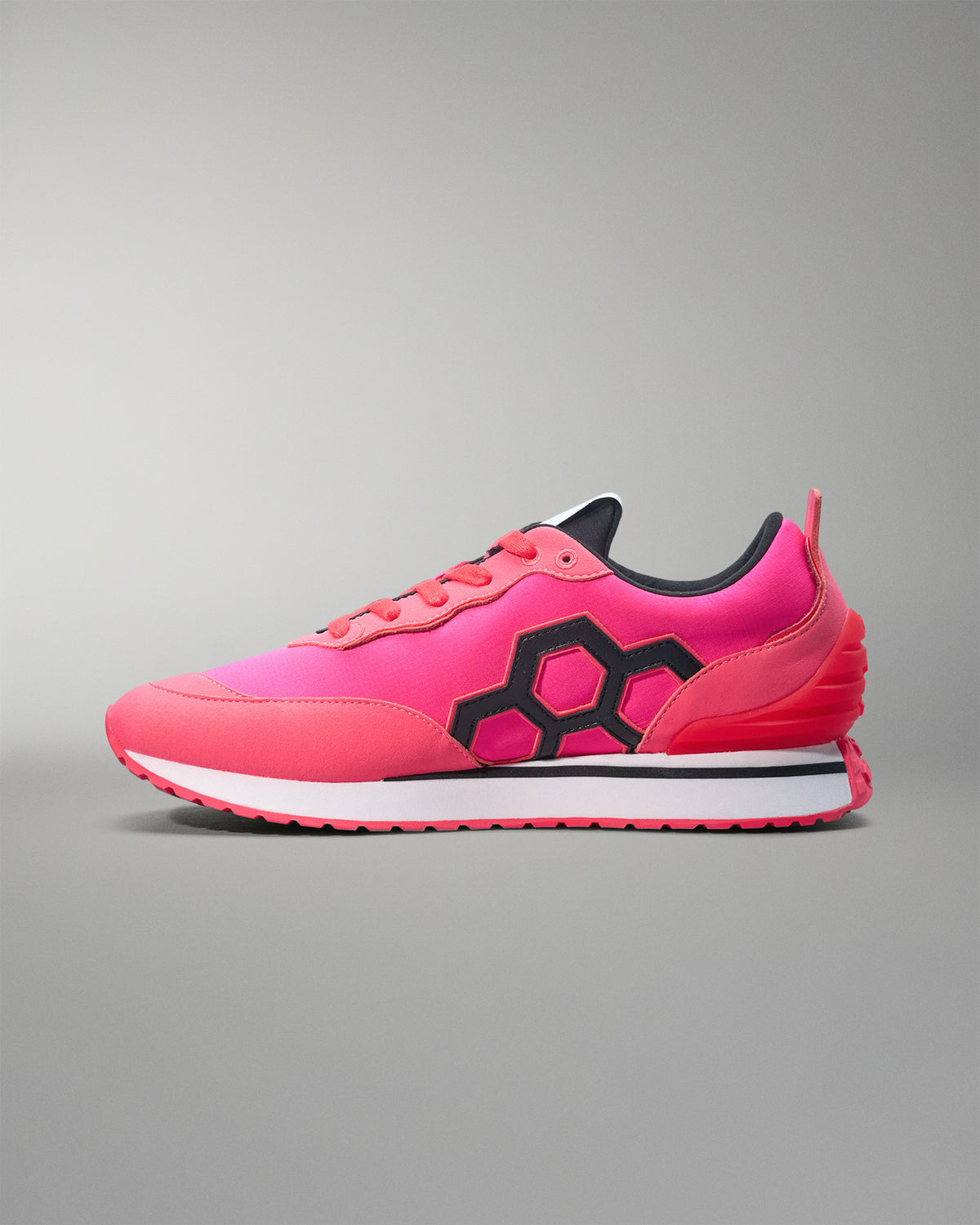 Pink running shoe with black hexagonal pattern on a gray background
