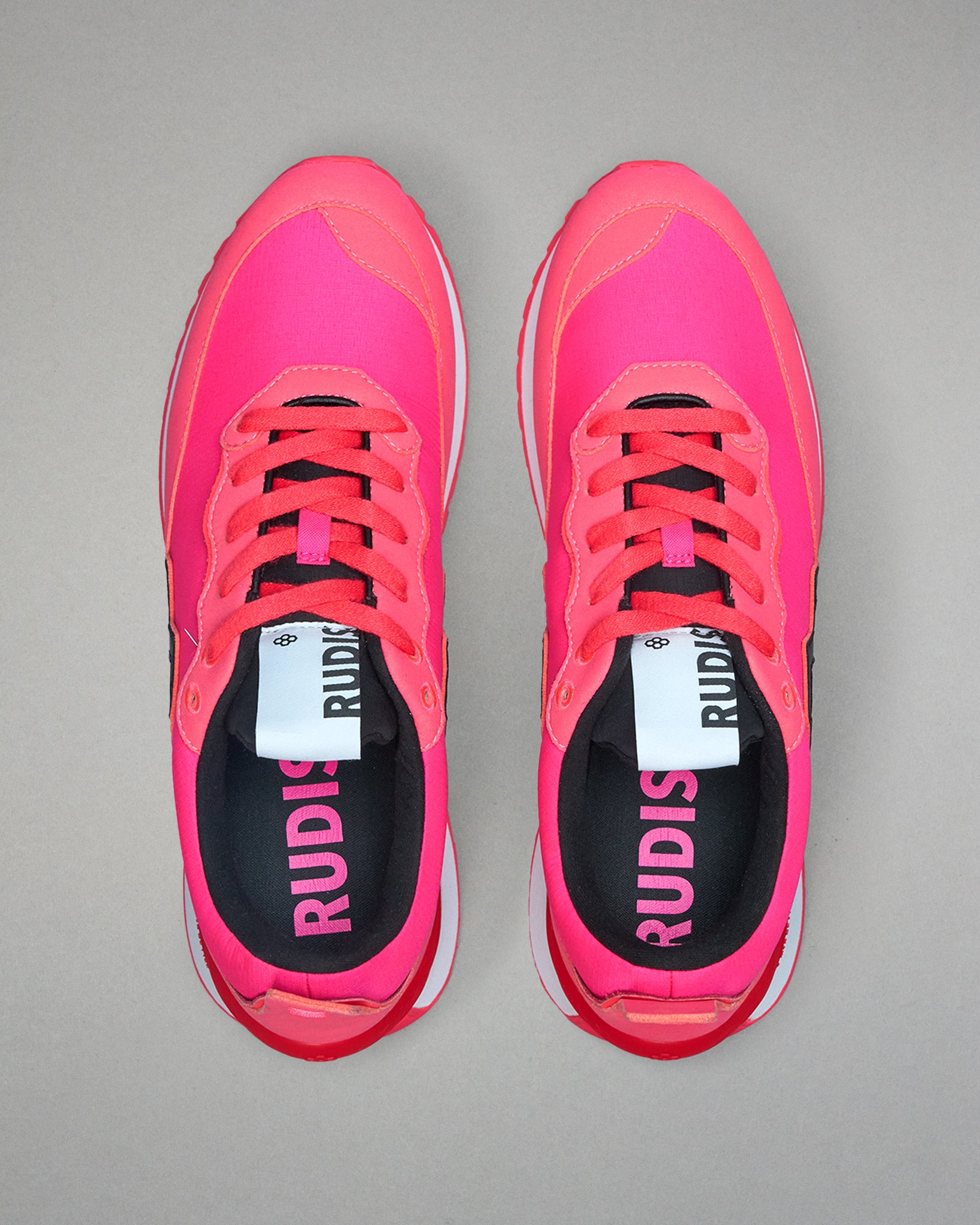 Pair of pink running shoes with visible brand name on a gray background