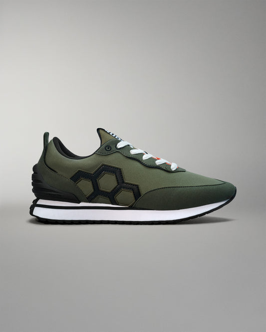 Green sneaker with black hexagonal pattern on a gray background